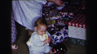 1972: baby boy's first christmas with family under tree opening presents
