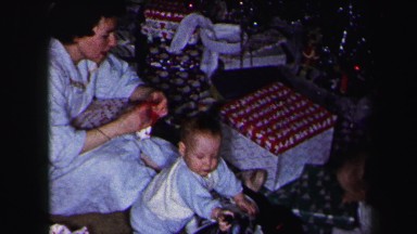 1972: family on the floor opening christmas gifts under the tree LYNBROOK