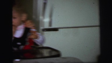 1972: twin babies in high chairs with mom, trying to make them smile