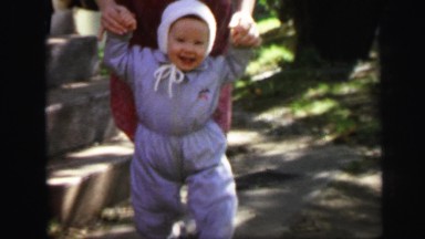 1972: woman in dress walking with smiling baby near set of stone stairs