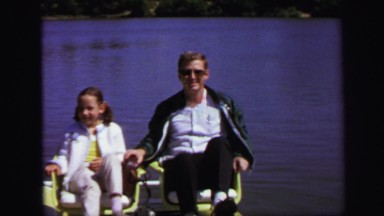 1972: young girl and man paddle across lake. LYNBROOK, NEW YORK