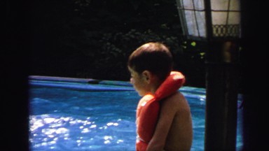 1972: kid wearing lifejacket swimming poolside LYNBROOK, NEW YORK