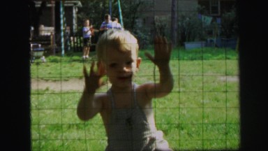 1972: group of kids in backyard by the swings and young child in overalls
