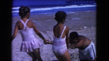 1960: two girls playing on the beach in the sand with dad FLORIDA