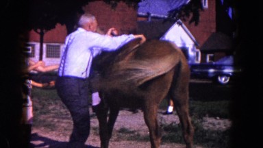 1960: an older man with gray hair climbing up onto a horse FLORIDA