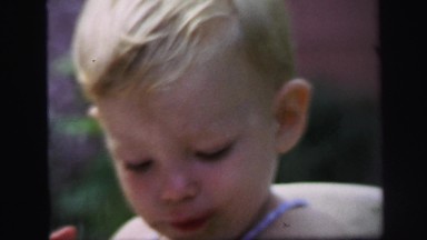 1972: cute little boy with messy face outdoor in high chair eating LYNBROOK