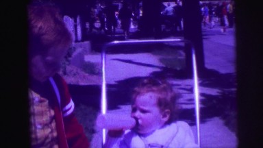 1974: redhead big brother pushing around kid sister in stroller on sidewalk