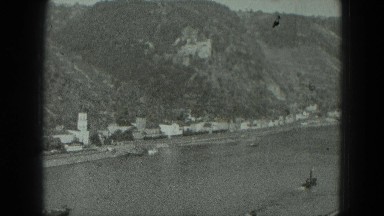 1951: View of River Canyon Boat with Mountain Towering Above and City Nearby