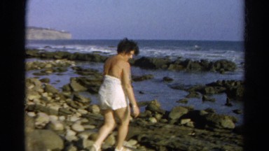1966: Woman Exploring Sea Shore Searches for Shells in Salty Ocean Water