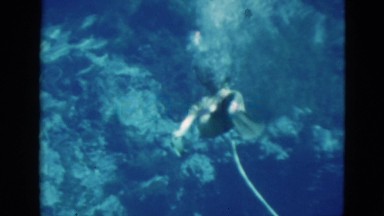 1952: two ladies are snorkeling and breathing underwater using large air tanks