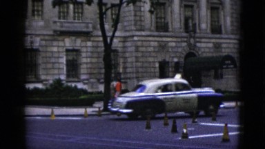 1952: flashback old classic cars driving in town with people walking