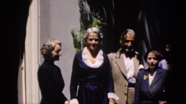 1952: dressed up adults standing outdoor staring at the camera CAMDEN