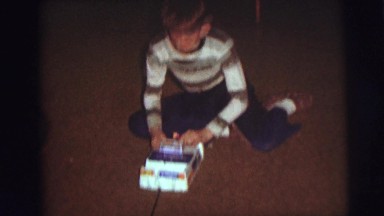 1974: a lean funny boy sitting on the ground playing electronic toy CAMDEN