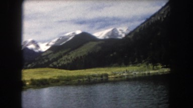 1962: Picturesque View from a Moving Car of a Lake and Snow-Capped Mountains