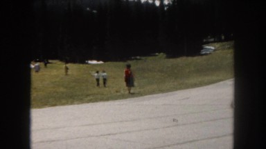 1962: people walking through a meadow with a beautiful mountain