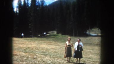1962: two women in dresses walking across the grass field. LAS VEGAS