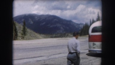 1962: a man walking toward a vehicle on the side of a road
