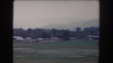 1962: view from a moving vehicle of landscape and scattered buildings