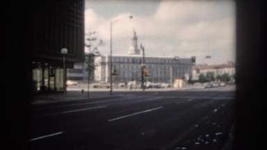 1962: a group of people expecting an event at the edge of a wide avenue