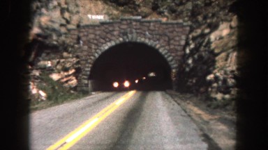 1962: a car is entering through a tunnel on a road passing other cars