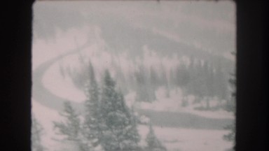 1962: a winding road covered in snow with pine trees on either side COLORADO