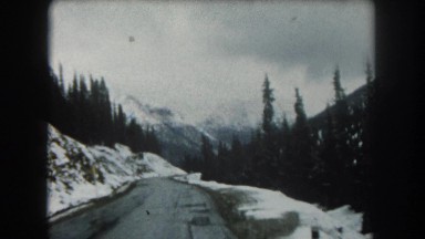 1962: an icy road with snow covered mountains on either side