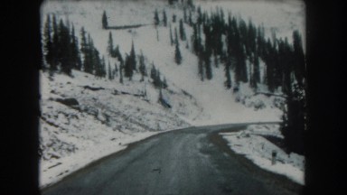 1962: a beautiful snow capped mountain ridge as seen from a moving vehicle