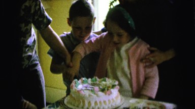 1964: a family is helping to a little girl to cut her birthday cake CAMDEN