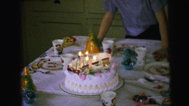 1964: child preparing to blow out candles on his birthday cake at a birthday