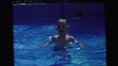 1964: kids playing in a backyard pool a boy dives underwater and then pops back