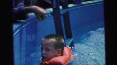 1964: child swimming in a pool with life preserver CAMDEN, NEW JERSEY
