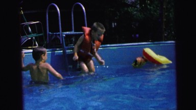 1964: young boy jumps into swimming pool with life jacket and makes a splash