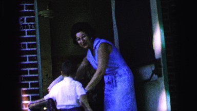 1964: a woman and a small boy wearing a bow tie observing the camera