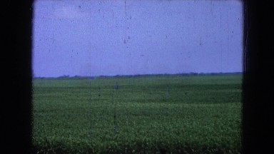 1965: vintage video of a large mountain with a vast grassy area in front of it.