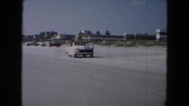1961: a group of people riding in a convertible on the beach MICHIGAN