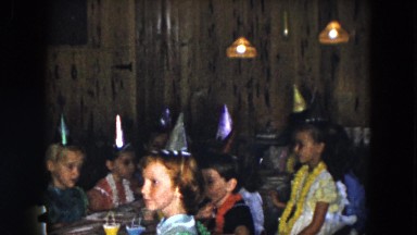 1961: various children with hats at a birthday party sitting around the table