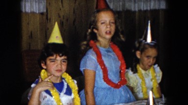 1961: little girls celebrating around table while wearing party hats and leis