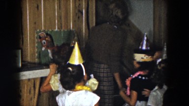 1961: several little girls wearing shiny birthday hats at a party indoors