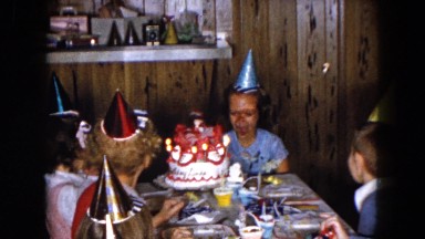 1961: young girl and her friends celebrating the blowing out of birthday candles