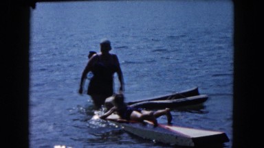 1961: mother watching over two children using flotation devices in the ocean