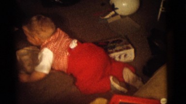 1964: happy child on floor surrounded by toys with man and two children by couch