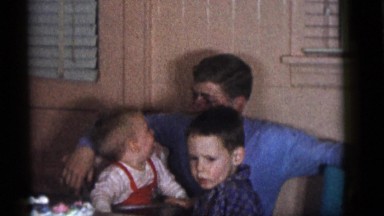 1964: a handsome young man in a blue sweater holding a baby in his lap CAMDEN