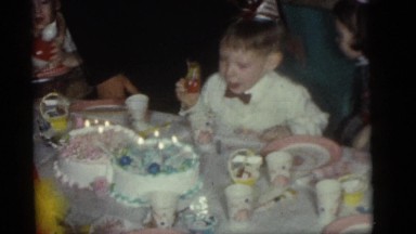 1964: a boy sitting at a table in front of a birthday cake with candles CAMDEN