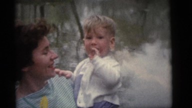 1964: Woman Carrying Toddler Placing Fingers in Mouth by Lake in Camden, NJ