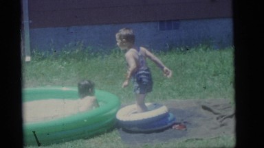 1964: two children playing in an inflatable pool in the yard of a house CAMDEN