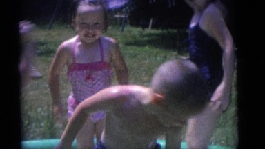 1964: several children playing outdoors in a small child's swimming pool CAMDEN