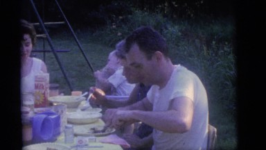 1964: a group of people eating happily in a vast courtyard with much greenery
