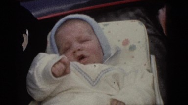 1964: father is holding his beautiful kid in his hand on a bed CAMDEN