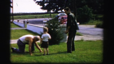 1956: young boy playing with older man working on lawn BOSTON