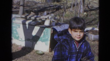 1963: Young Boy Blinking and Smiling Near Block Structure in Yard